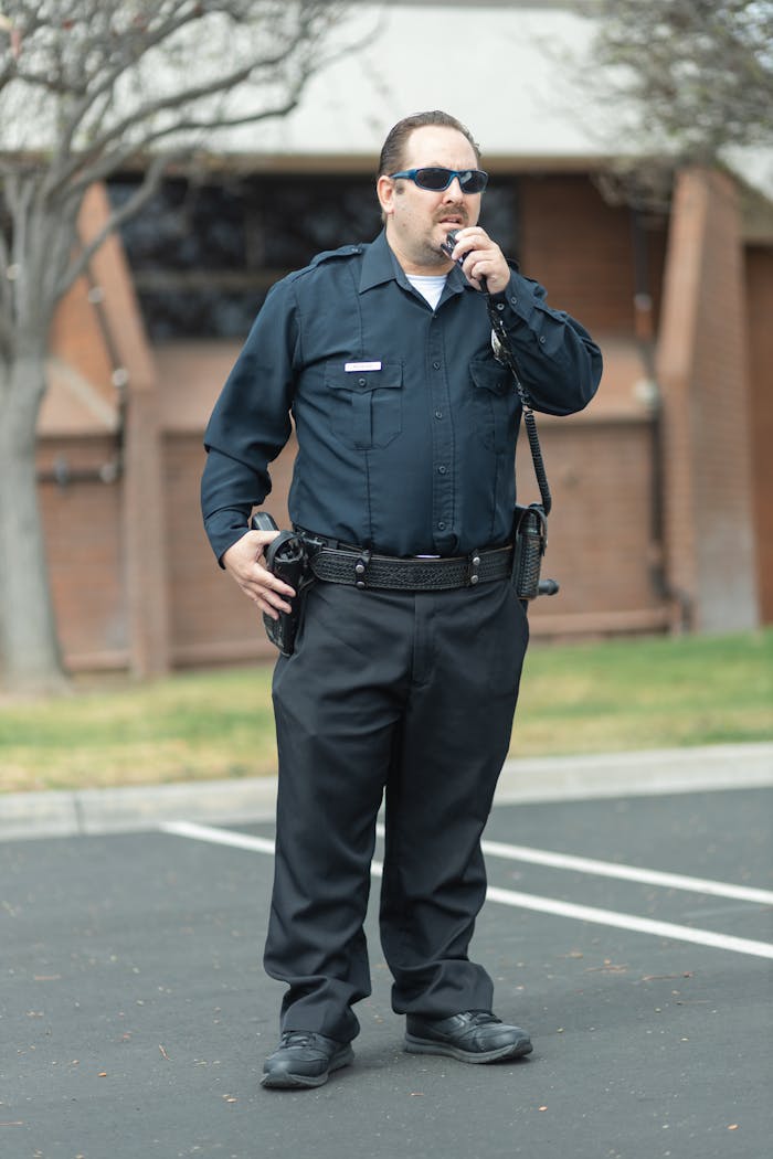 A police officer in uniform communicates via radio, exuding public safety authority.